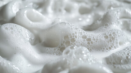 Close-up of a shampoo bottle covered in white foam, with bubbles overflowing on the side.