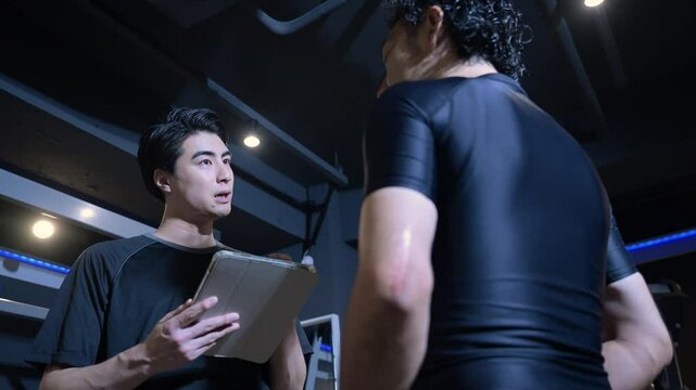 Trainer teaching with a tablet in a training gym Video of an image of a personal trainer or instructor teaching a client
