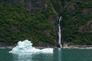Waterfall and iceberg from Sawyer glacier floating in Tracy Arm fjjord in Alaska near Juneau