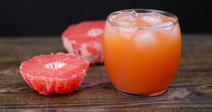 freshly squeezed juice in a glass and ripe red grapefruit on a black table, peeled juicy red grapefruit