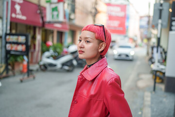 Gen z girl leather fashion with punk Asian woman tourist of local city Southeast Asia travel trendy pink hairstyle young female punk traveler walking around in town