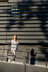 Fototapeta premium Business woman walking confidently along modern outdoor architecture in stylish attire during golden hour