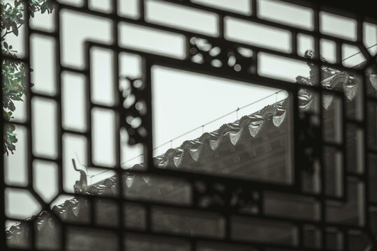 A glimpse of a tiled roof viewed through a traditional Chinese window in Suzhou.