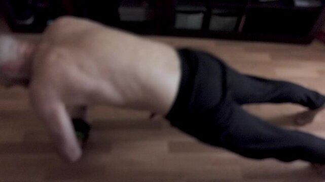 A man does an abdominal exercise using a gymnastic wheel in his room