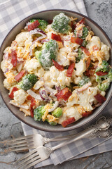 Steamed Broccoli, Cauliflower Salad with Bacon, onion, cheese and mayonnaise dressing closeup on the plate on the table. Vertical top view from above