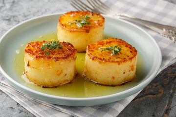 Fondant potatoes are a traditionally French potato dish where you pan sear potatoes, then braise in butter, garlic, herbs and stock closeup on the plate on the table. Horizontal