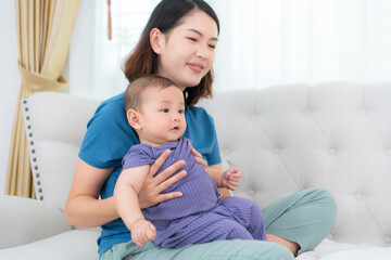 Fototapeta premium A mother lulls her little child to sleep on the sofa in the living room of the house