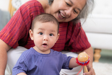 Fototapeta premium Grandmother and their little grandchild play happily in the living room of the house