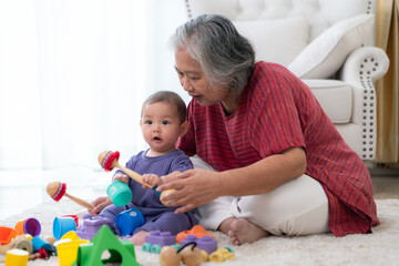 Grandmother and their little grandchild play happily in the living room of the house