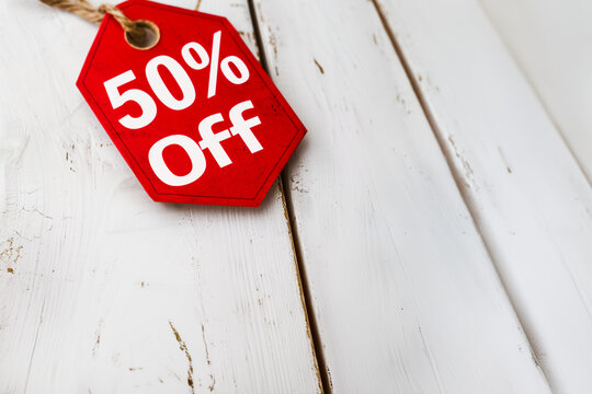 &Eacute;tiquette de r&eacute;duction texte en anglais '50% Off' en rouge vif, attach&eacute;e par une ficelle sur surface en bois blanc, symbolisant des soldes ou une promotion Black Friday