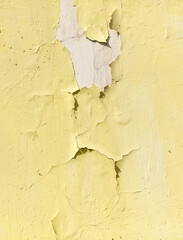 Cracked yellow paint on the wall as an abstract background. Texture