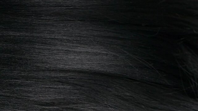 Closeup human long hair texture in slow motion, black straight hair background