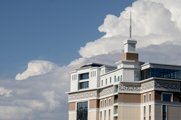 Fragment of the building's architecture against the background of blue sky with white clouds....
