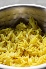 Pilau rice, used with Indian curry dishes, in a metal bowl dish.  On a grey concrete background