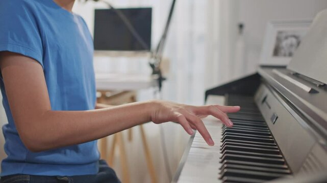Close up of Asian child playing electronic piano in music record studio. 