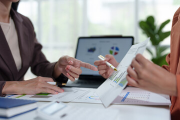 Team of Asian businesswomen analyze and brainstorm using calculators Financial data pointing hand on sheet. Graph chart showing income on laptop. Concept of teamwork process, growth.