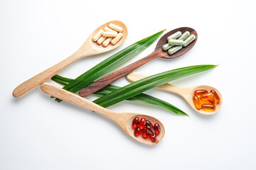 Different pills, herbs vitamin and mineral pills in wooden spoon flat lay Dietary supplements