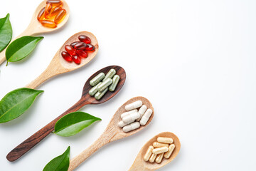 Wooden spoon with assorted herbal vegan vitamin capsules for healthy lifestyle with fresh leaves
