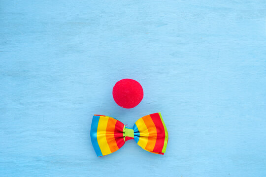 Clown nose and bow tie on blue wooden background. Decorations for April Fools' Day..