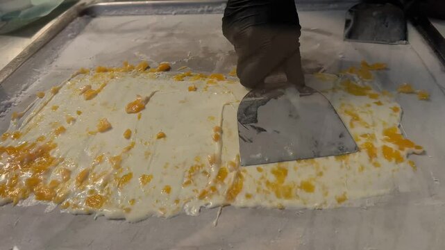 Thai roll ice cream is made by hand in black gloves on the freezer. Sweet dessert made from natural berries and ingredients. The process of making food. The art of cooking Thai ice cream on the street