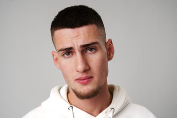 Obraz premium Sad Young Man Looking at Camera against gray background
