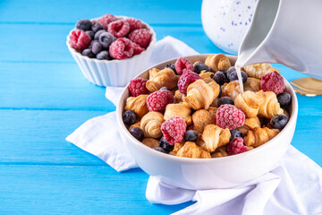 Tiny breakfast croissant cereals with fresh berries and milk