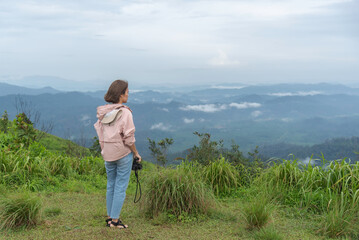 Naklejka premium Traveler sightseeing the beautiful scenery of nature and mist during time the sunrise