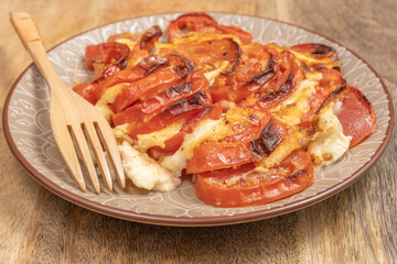 Baked tomatoes with mozzarella cheese on ceramic plate.
