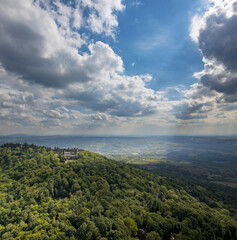 A mountain range with a cloudy sky and a few houses in the distance