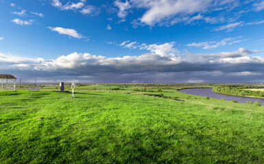 Obraz premium A large field of grass with a river running through it