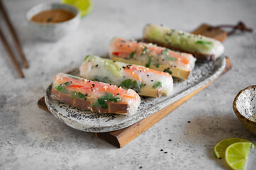 Summer rolls with fresh vegetables and smoked tofu served with peanut sauce and lime. Vietnamese appetizer. Spring rolls. Healthy food concept. Snacks, finger food. Close up.