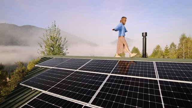 A woman joyfully walks across a solar-paneled roof, embracing the freedom of sustainable, off-grid living surrounded by nature's beauty on a foggy morning