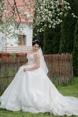 A woman in a white wedding dress is standing in a field of flowers. She is wearing a veil and a necklace