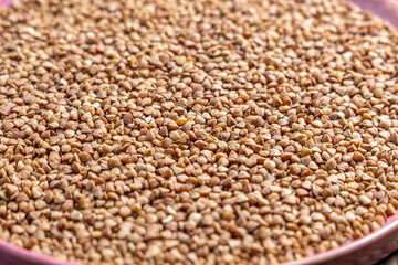 Buckwheat Grains on Plate on Wooden Background, Top View, Copy Space.Hulled kernels of buckwheat grains close up. Food background.