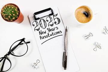 New year resolutions 2025 on desk. 2025 goals list with notebook, coffee cup, plant on white table. Resolutions, plan, goals, action, checklist, idea concept. New Year 2025 resolutions, copy space