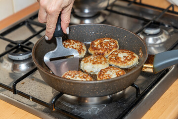 Meat burgers or cutlet-shaped patty being shallow fried in oil on a frying pan, close up. version of cutlets - kotlety.