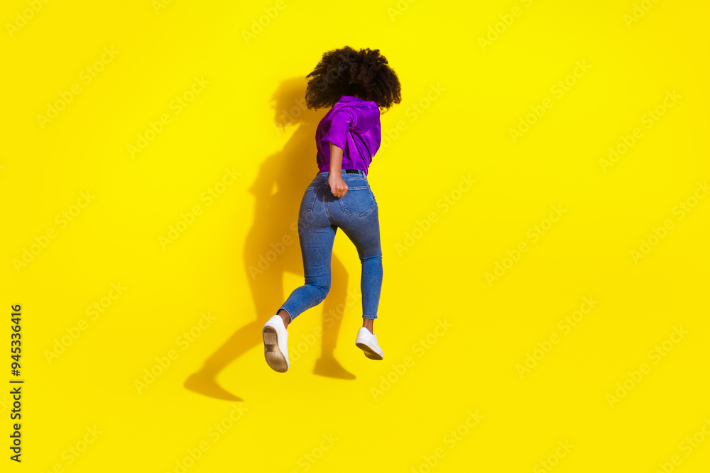 Wall mural Full body photo of pretty young girl running behind view wear trendy violet outfit isolated on yellow color background