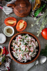 Hearty dinner: homemade salad with tomatoes, beef, fresh herbs and cream sauce in a brown plate on a gray background. For lunch - salad with meat and vegetables. Vertical photo. View from above
