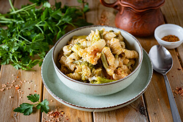 Pasta with cauliflower and broccoli on a plate on a wooden table. Lunch for the whole family. Close-up. Pasta with vegetables for dinner.