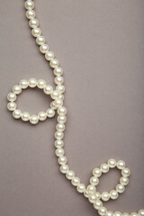 Elegant pearl necklace on grey background, top view. Space for text