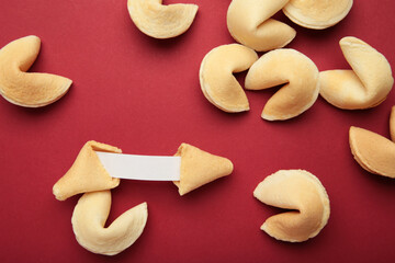 Tasty fortune cookies and paper with prediction on red background. Top view