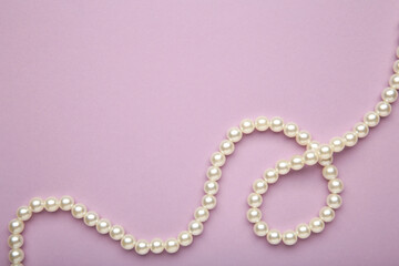 Elegant pearl necklace on purple background, top view. Space for text