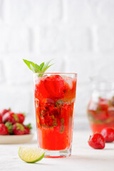 Fresh cocktail with strawberries, mint and lime in a glass. Strawberry mojito. Refreshing red drink, sugar free. Vertical orientation.