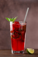 Fresh cocktail with strawberries, mint, ice and lime on a brown background. Strawberry mojito. Refreshing red drink, sugar free. Vertical orientation.