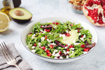 A plate with green rocket salad with pomegranate and avocado