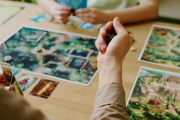 High angle closeup of unrecognizable man holding dice in hand while playing modern fantasy board...