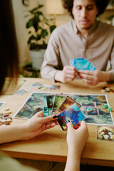 Vertical shot of unrecognizable woman holding cards in her hands playing thematic board game with...