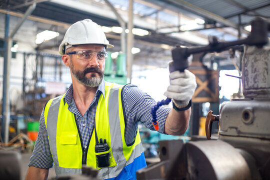 Engineer worker man wearing uniform safety and white hard hat working machine lathe metal in factory industrial, engineer workers manufacturing industry. repair service man at workshop.