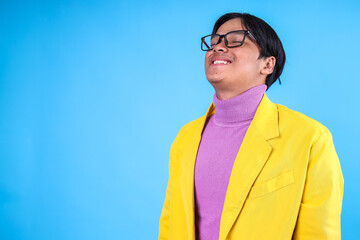 Asian Man Closing Eyes While Smiling Feeling Relieved on Blue Background