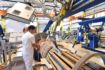 young mechanical engineering workers operate a machine for winding copper wire - manufacture of...